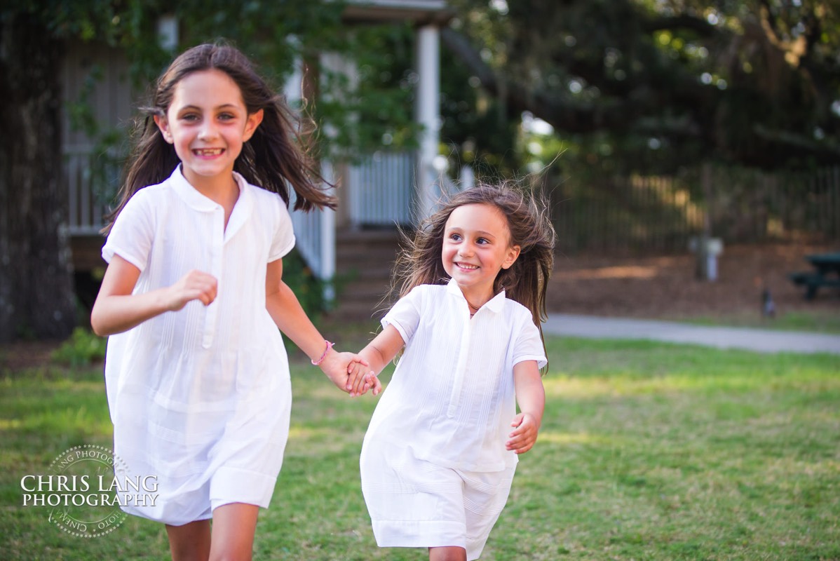 Two young gorls holding hands walking in the park at Old Baldy - Places for family vacation - Bald Head Island Photographers - BHI Photography - Kids Portraits -  Pictures on Bald Head Island - BHI Photo Services - Chris Lang Photography 