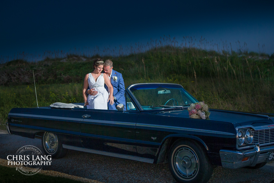 Image of Bride& Groom in convertable  siting in the back seat hugging eachother - Lifestyle Wedding Photography - Wilmington NC Wedding Photographers