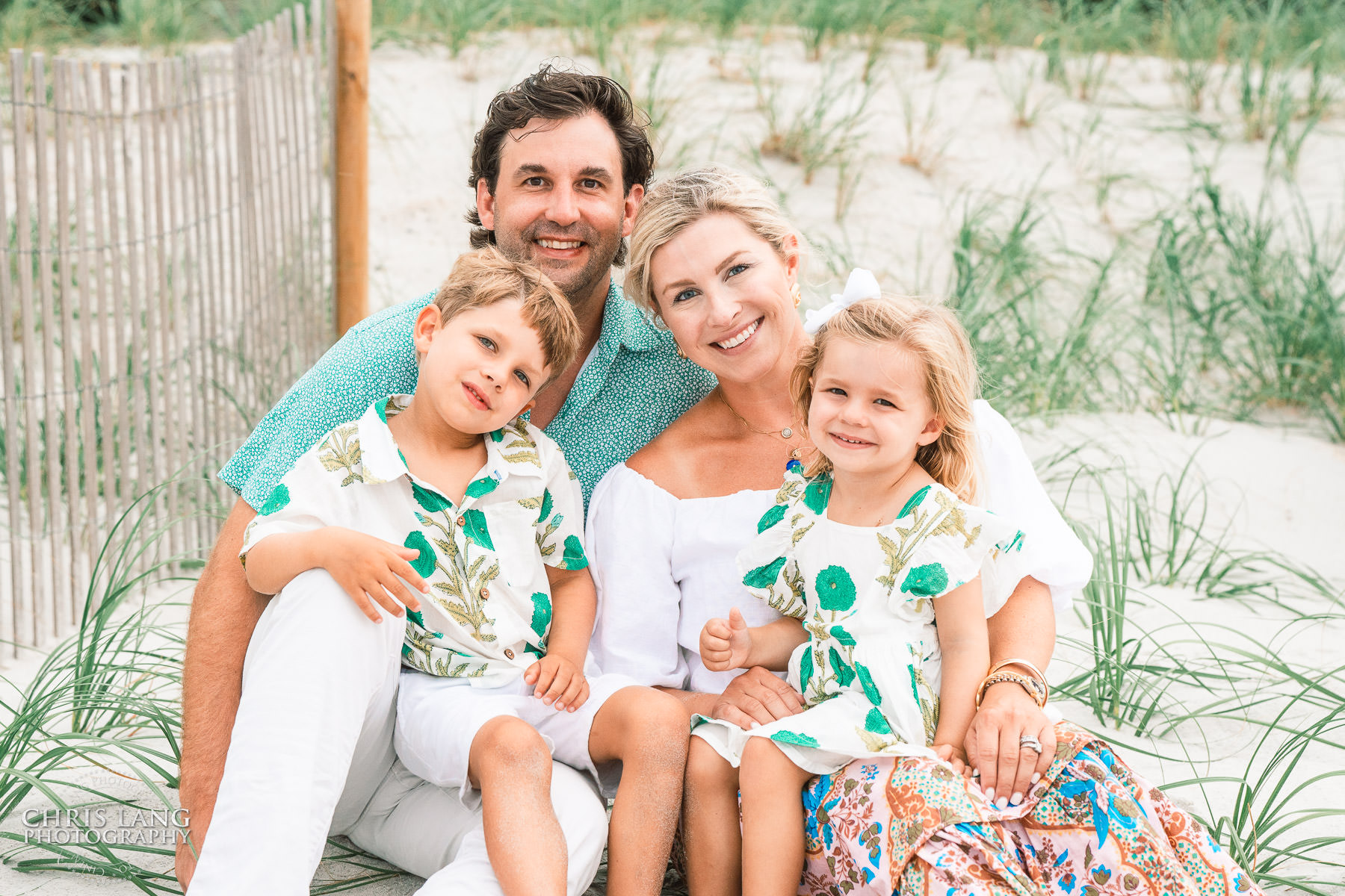 Image of family sitting on the beach dunes.  Outfit ideas for family beach photography - Wrightsville Beach Family Photography - Wrightsville Beach Photographers - Beach Family Photos- Chris Lang Photography   