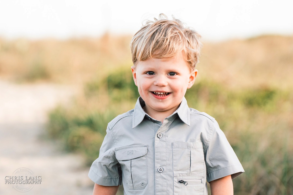Image of young boy om the beach  with beach dunes in background - Wrightsville Beach Family Photography - Wrightsville Beach Photographers - Beach Family Photos- Chris Lang Photography  