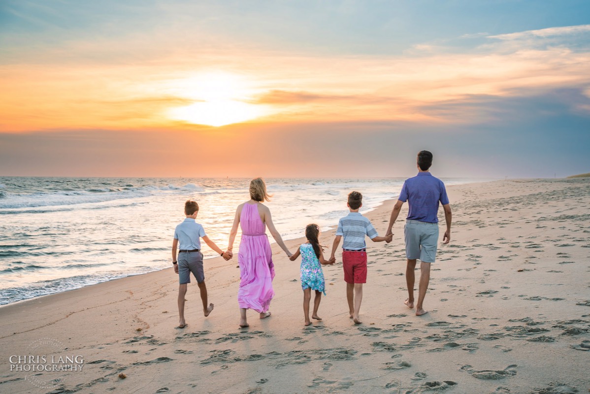 image of family walking in the beach holding hands during golden hour - Wrightsville Beach Family Photography - Wrightsville Beach Photographers - Beach Family Photos- Chris Lang Photography  