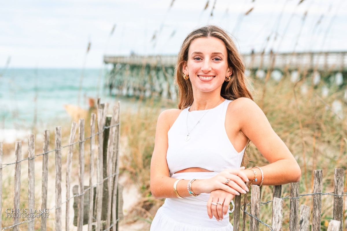 photo of highschool senior girl leaning on beach path fence in white dress - beach photo ideas for highschool seniors - Wrightsville Beach High School Senior Photography - Wrightsville Beach Photographers - Beach Senior Portrait  Photos- Chris Lang Photography  