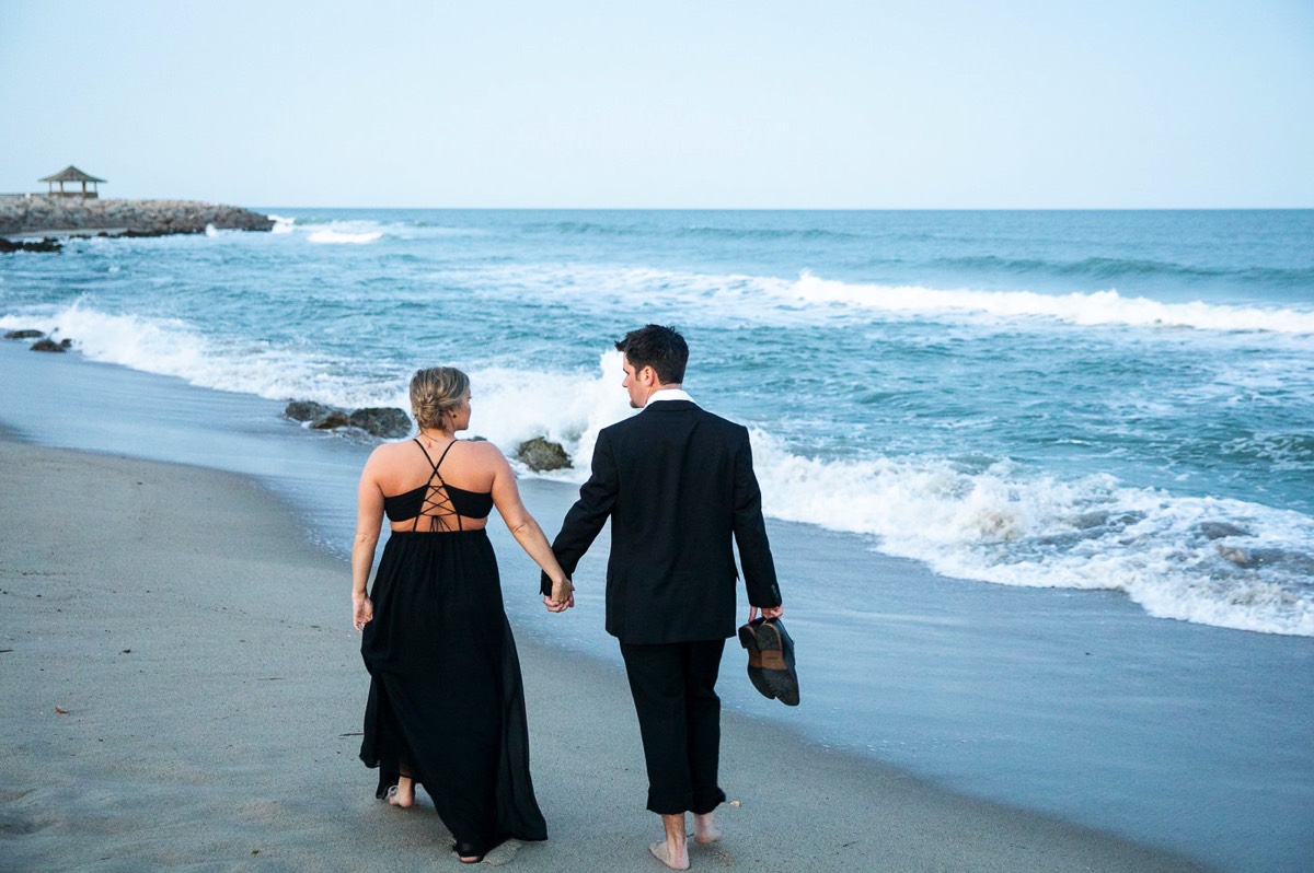 Couple in formal wear walking on the beach - Engagement photo - Couple wrapped  in Christmas lights on the beach - Fort Fisher North Carolina -  Engagement Photography - Wedding Ideas - Popular engagement photography locations - Lifestyle engagement photo -  Ft Fisher engagement photographers - Engagement session ideas - New trends in engagement photography - Chris Lang Photography - Engagement photos 