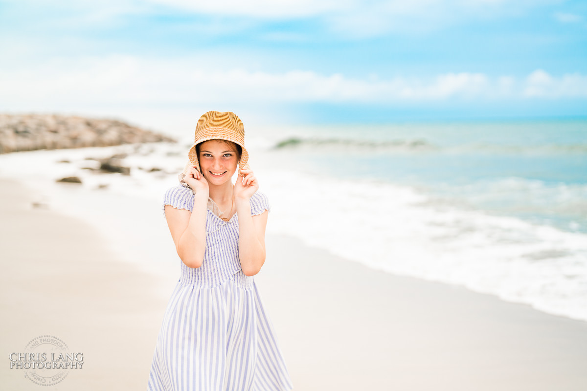 photo of girl holding a sunhat on the beach at